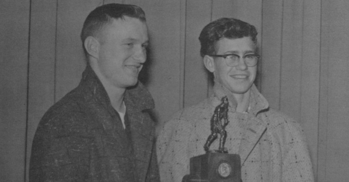 Two men standing next to each other holding a trophy.