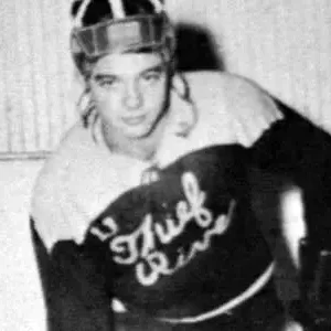 A man in hockey uniform with helmet and gloves.