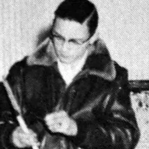 A man in a leather jacket writing on paper.