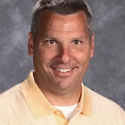 A man with gray hair and an orange shirt.