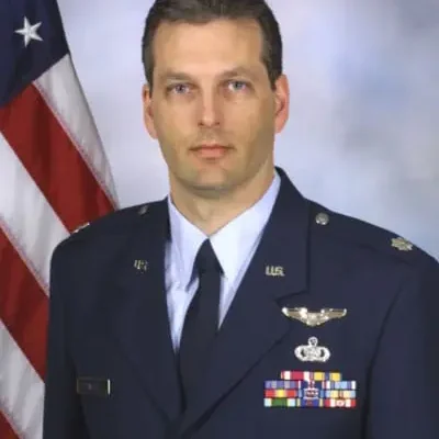 A man in military uniform standing next to an american flag.