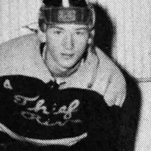 A man in a hockey uniform is leaning on the wall.