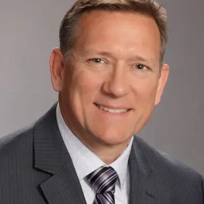 A man in suit and tie smiling for the camera.