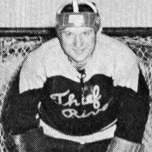 A man in hockey uniform sitting on a couch.